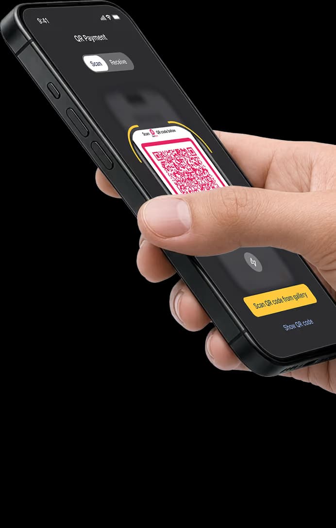 A hand holding a phone with bank app QR scanner open ready to scan merchant phone with DuitNow QR code